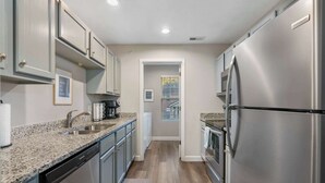 A modern kitchen with stainless steel appliances, granite countertops, and light wood flooring.