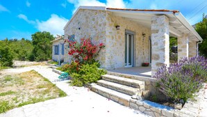 A stone house with a porch, steps leading to the entrance, and a garden with flowers. - Villa Labovitsa in Paxi (Paxos)