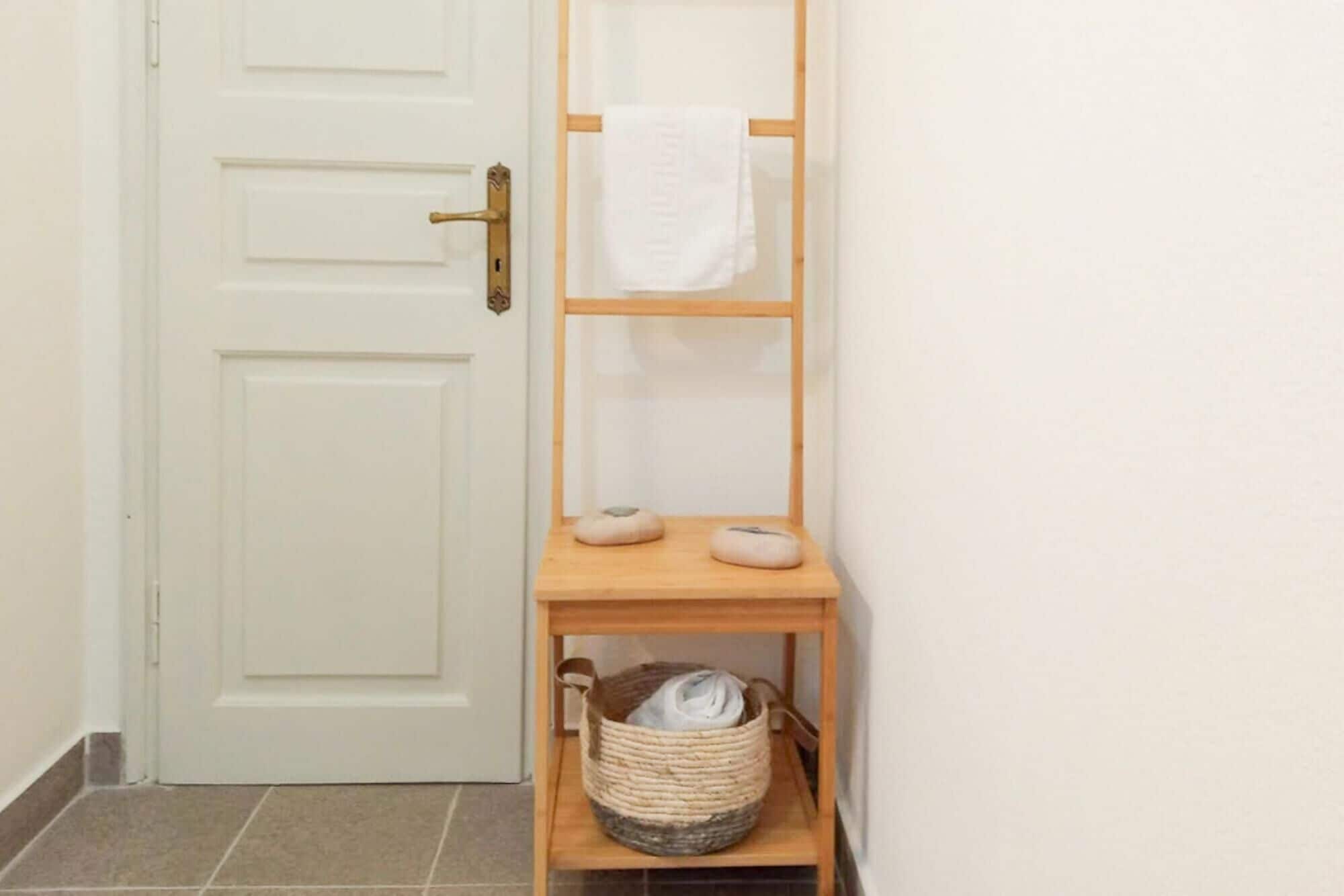 A hallway with a white door, a wooden shelf with a towel, and a woven basket.