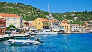 A coastal town with colorful buildings, a marina with boats, and a hillside in the background. - Villa Labovitsa in Paxi (Paxos)