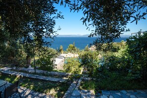 A view of a coastal area with a stone pathway leading to a seating area. - Antigoni Villa Ena in Longos (Paxos)