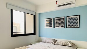 Une chambre à coucher avec un lit, une fenêtre et trois tableaux encadrés accrochés au mur.