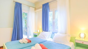 A double bed with blue and white bedding, two rolled towels, and a nightstand with a lamp. - Villa Natasha in Nisaki (Corfu)