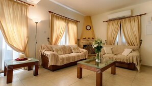 Ein Wohnzimmer mit zwei Sofas, einem Glastisch und einem Kamin.