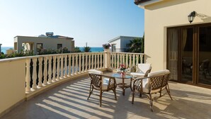 Ein Balkon mit Tisch und Stühlen mit Blick auf das Meer.