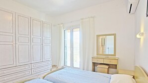 Quarto de hotel com duas camas, um guarda-roupa grande, uma toucador com espelho e uma janela com cortinas.