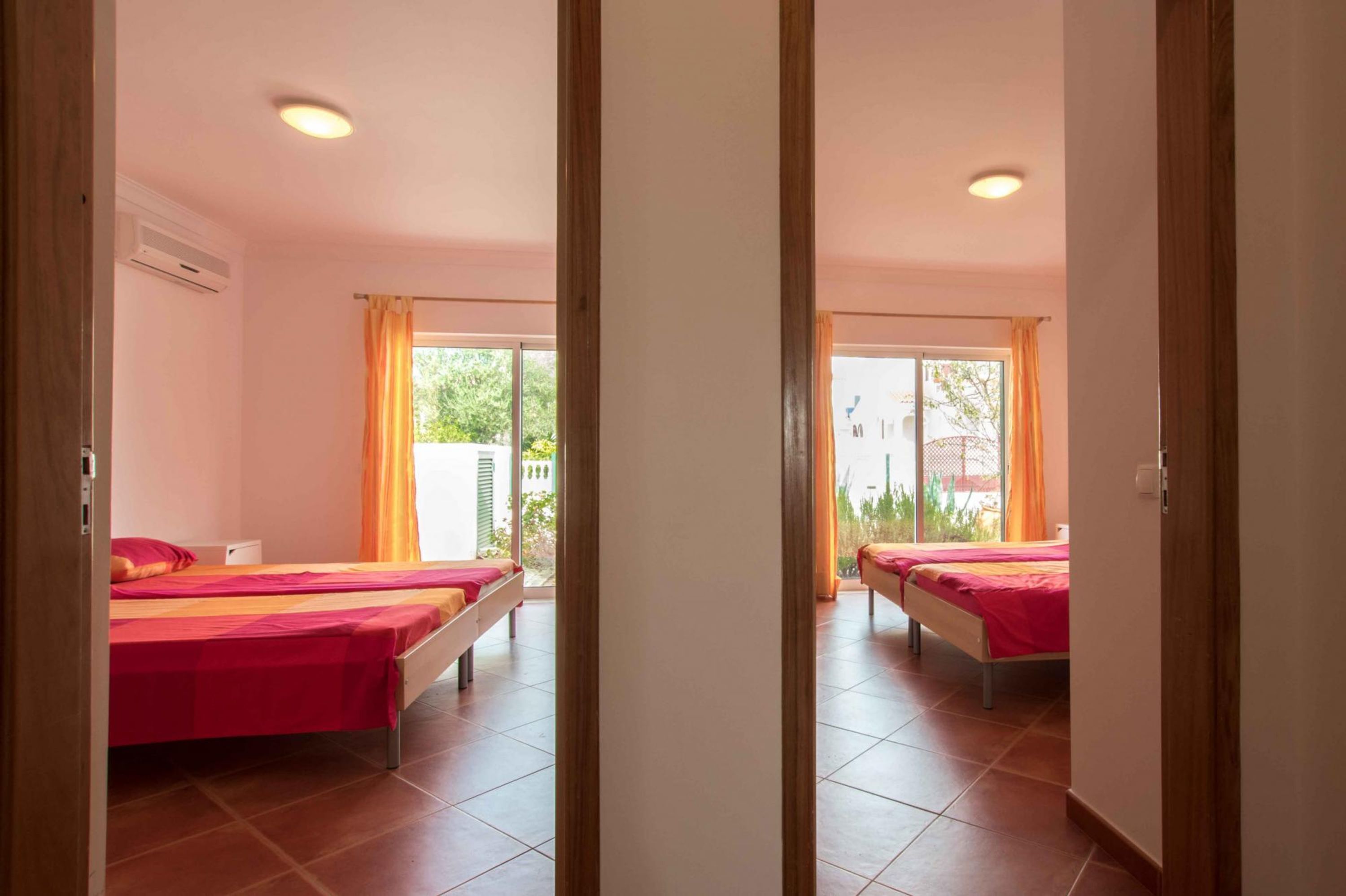 A room with two beds, a sliding glass door to an outdoor area, and a ceiling fan.