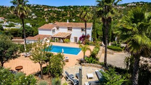 Eine Villa mit Pool, Gartenmöbeln und üppiger Bepflanzung.