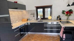 Une cuisine moderne avec des meubles de couleur sombre, un pare-feu décoré et un sol carrelé.