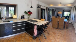 Une cuisine moderne avec un revêtement mural noir et blanc, un îlot central et un coin repas doté de chaises en osier.