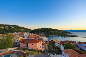 A coastal village with traditional Mediterranean architecture, including terracotta-tiled roofs and pastel-colored buildings.