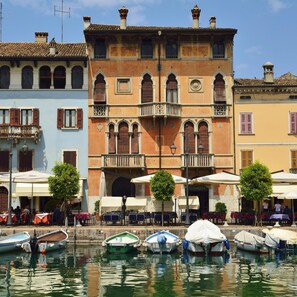 A historic building with a balcony and a door, surrounded by water and boats.