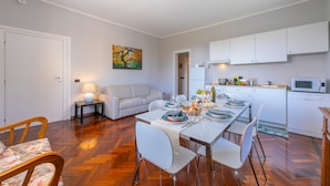Uma cozinha moderna com armários brancos, micro-ondas e uma área de refeições com mesa posta para quatro pessoas.