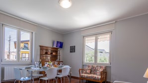 Uma sala de estar espaçosa com uma mesa de jantar, cadeiras, sofá e televisão.