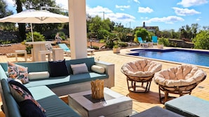 A poolside area with a sofa, chairs, and a small table. - Villa Santa Barbara by Portucasa (Faro)