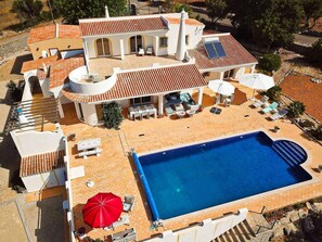 Una gran villa con piscina, zona de estar exterior y porche cubierto.