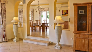 A spacious hallway with a dining area, featuring a staircase, two lamps, and a wooden cabinet. - Villa Santa Barbara by Portucasa (Faro)