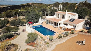 A villa with a swimming pool, outdoor seating, and a view of the surrounding landscape. - Villa Santa Barbara by Portucasa (Faro)
