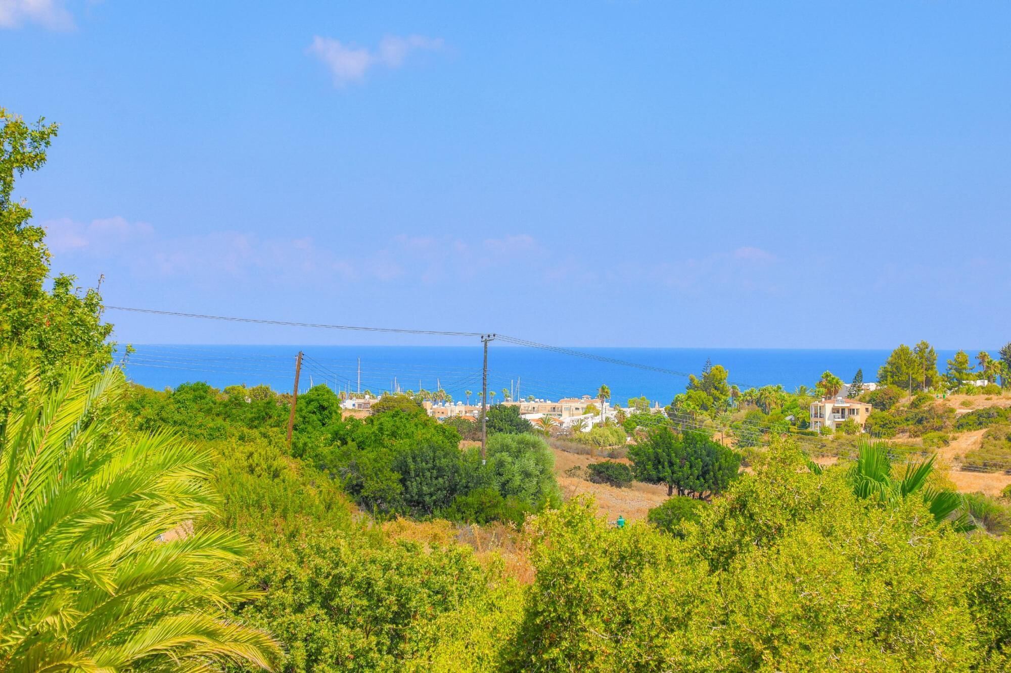 Ένα παράκτιο τοπίο με σπίτια, πλούσια βλάστηση και έναν καθαρό ουρανό.