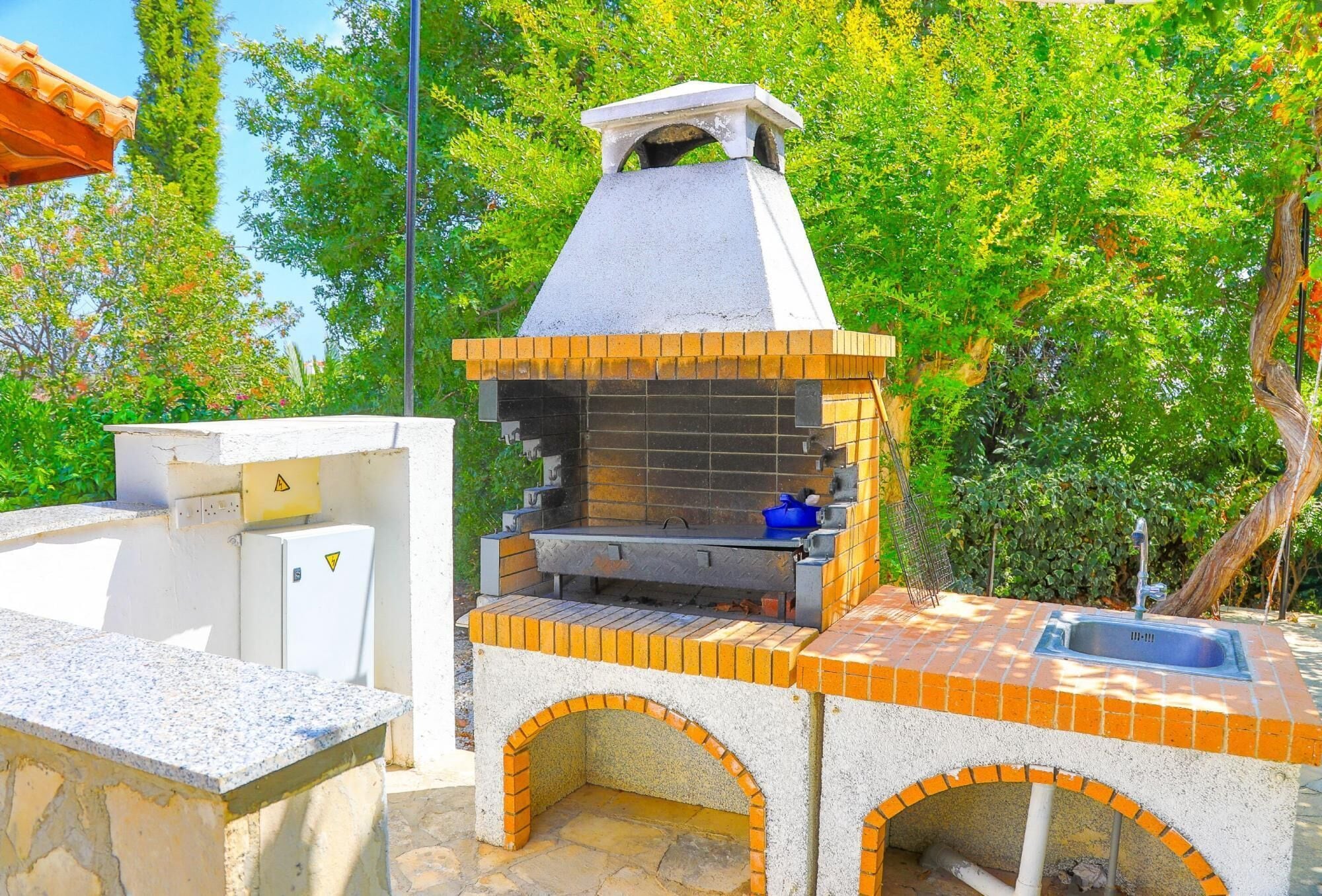 Cocina exterior con chimenea, pileta y horno empotrado.