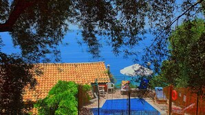 Ein Poolbereich mit einem geflasten Dach, einem Zaun und Blick aufs Meer.