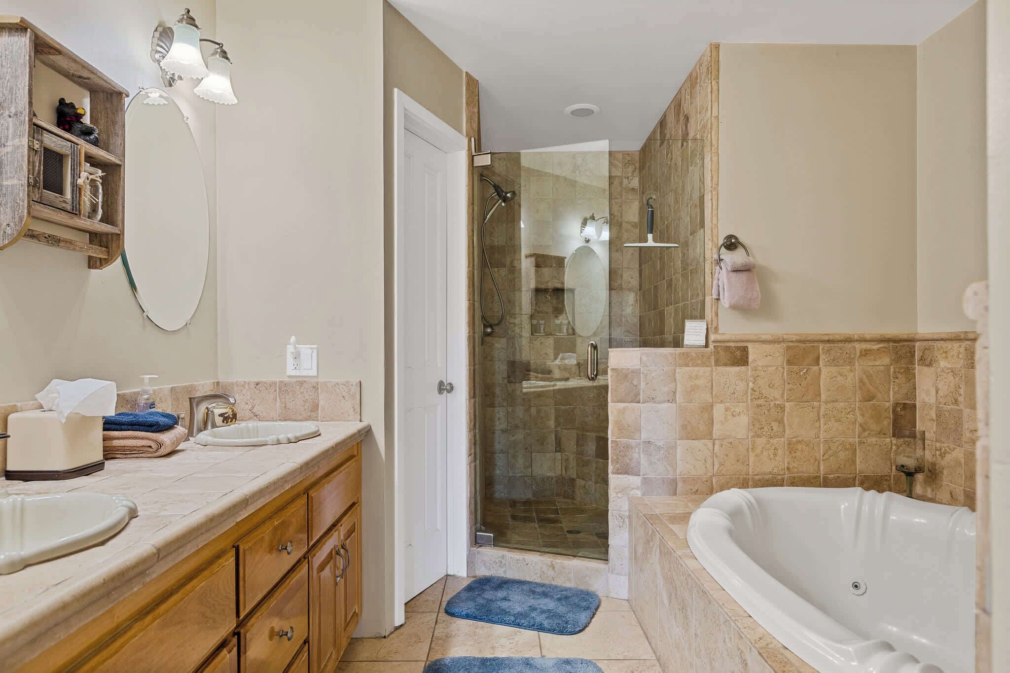 A bathroom with a shower, a bathtub, a vanity with a sink, and a mirror.