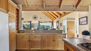Une cuisine avec des armoires en bois, une cuisinière encastrée et une vue sur l’extérieur.