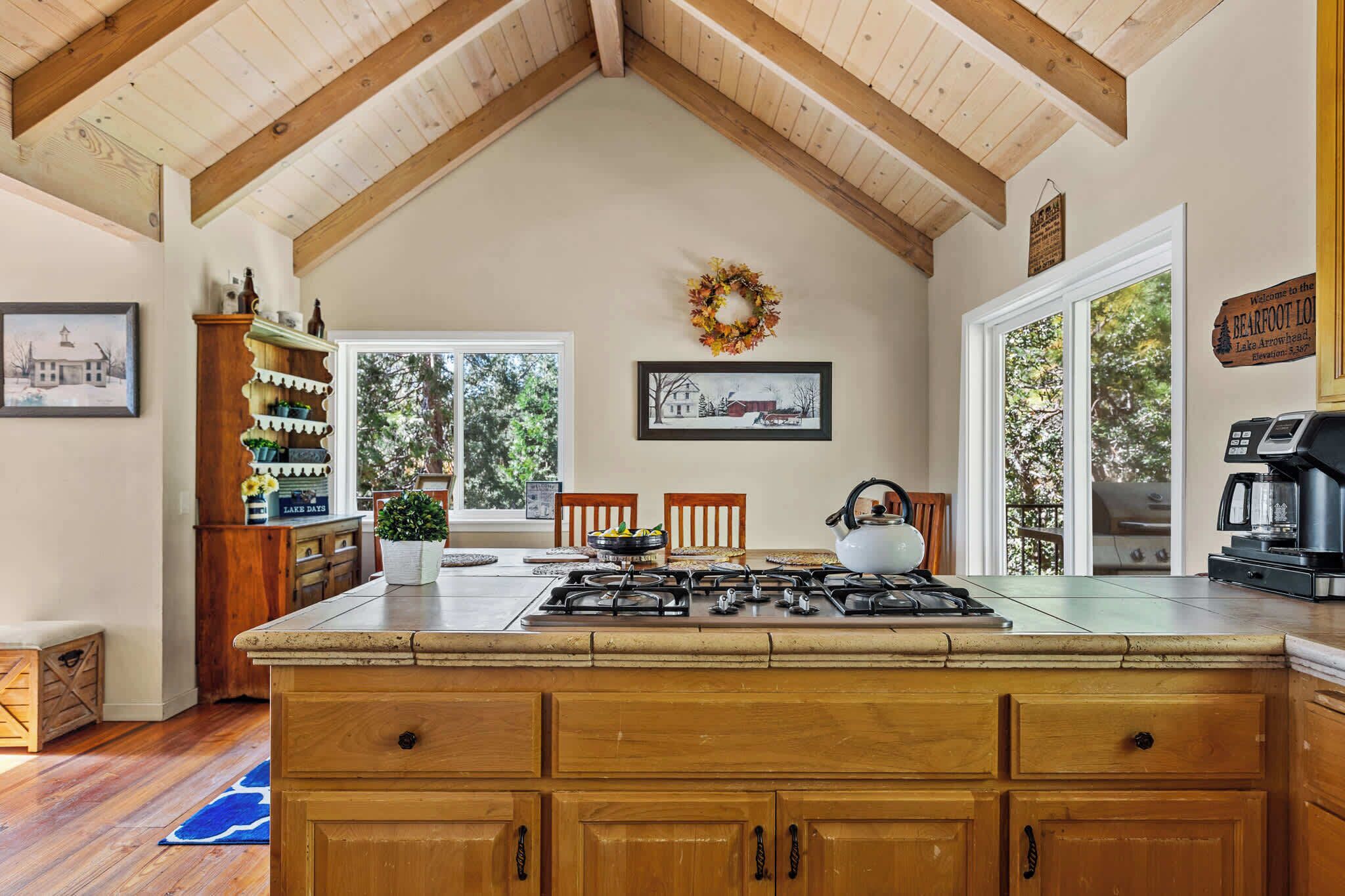 A kitchen with a large island, wooden cabinets, a gas stove, and a view of the outdoors.
