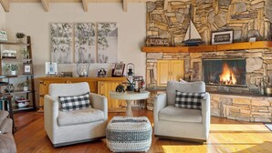 Un salon chaleureux avec deux fauteuils, une cheminée et un mur en pierre.