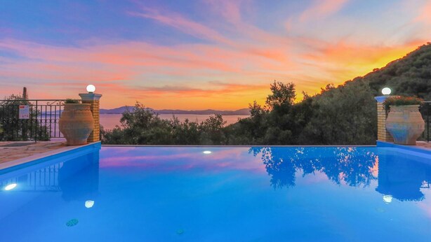 Une piscine à débordement offrant une vue imprenable sur le coucher de soleil sur l’eau.