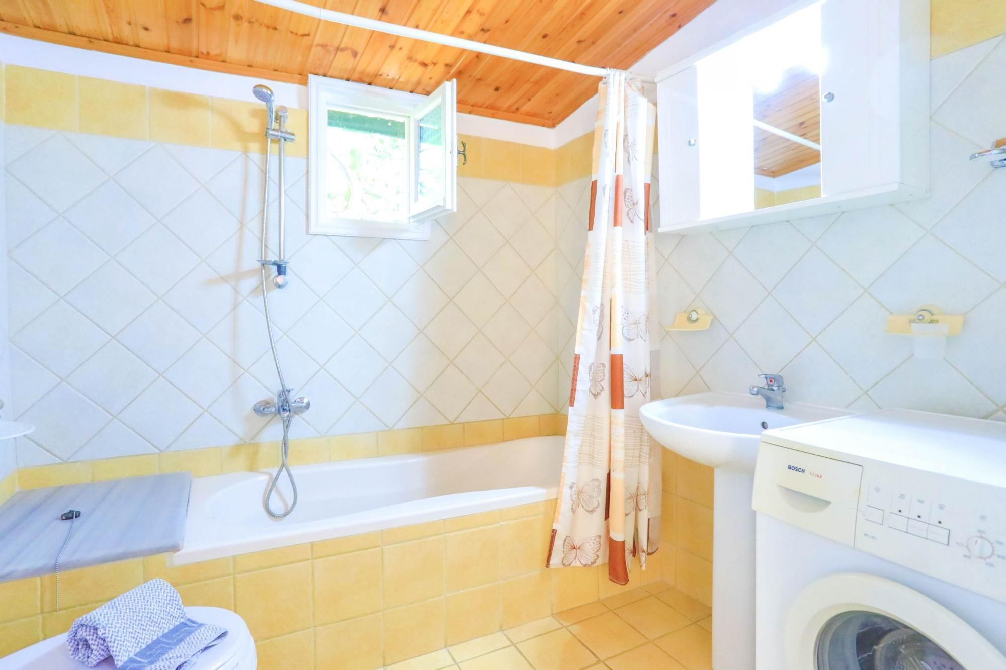Een badkamer met een bad, douche en een wasmachine.