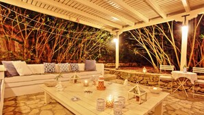 An outdoor seating area with a stone floor, white furniture, and decorative lanterns. - Lili Luxury Cottage in Ozias (Paxos)