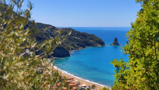 Eine Küstenstadt mit Strand, felsigen Klippen und einer kleinen Insel.