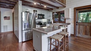 Una cocina moderna con electrodomésticos de acero inoxidable, una isla grande con taburetes de bar y un techo de madera rústica.