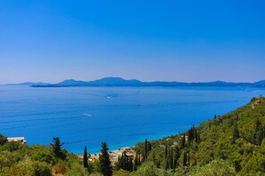 A coastal view with a clear blue sea, distant mountains, and dense green vegetation. - Vista Mare Assinia in Kentroma (Corfu)