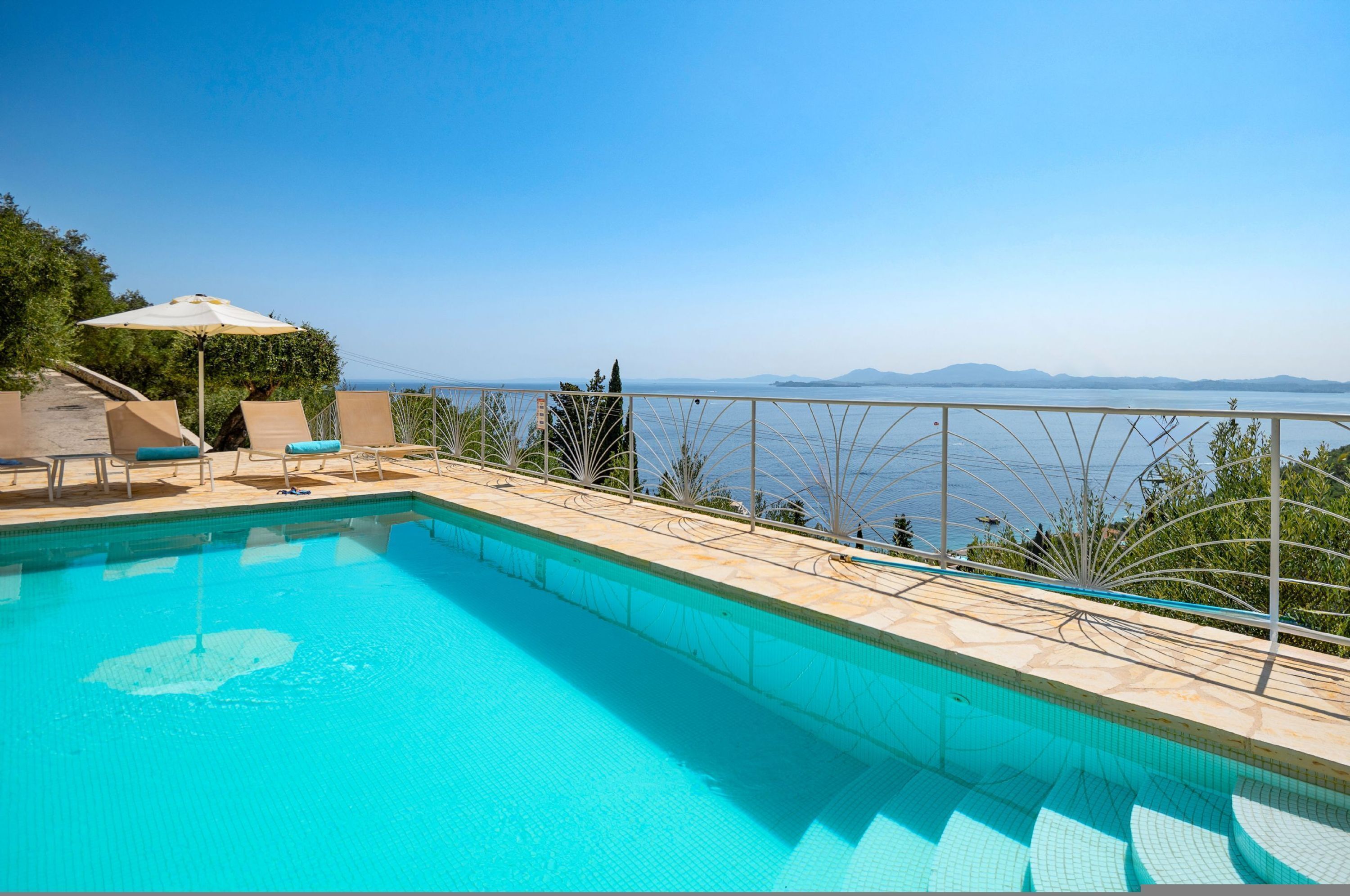 Una piscina con vista despejada al mar y montañas distantes.