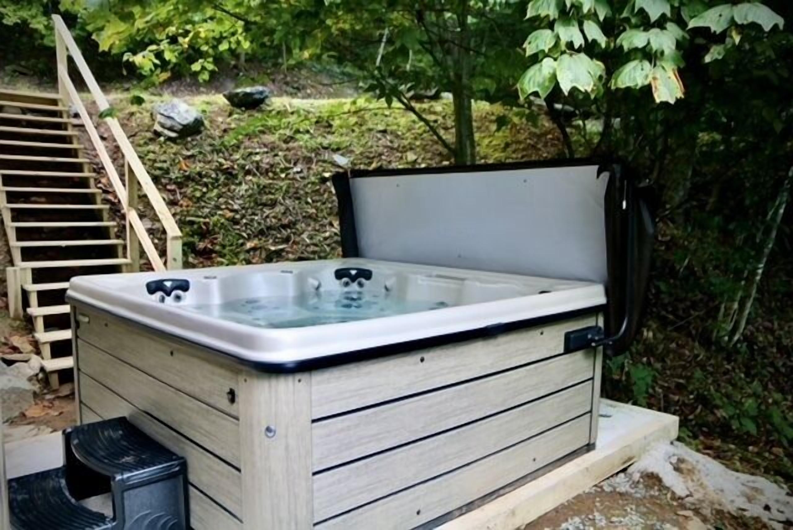 A hot tub with a wooden exterior, a ladder, and a natural outdoor setting.