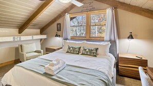 Une chambre à coucher avec un lit, une chaise, une table de chevet et une fenêtre avec des rideaux.