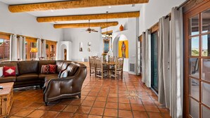 A spacious living area with a brown leather sofa, a dining table with chairs, and a ceiling fan. - Stunning Views, Pool, Sauna, Steam Shower, Firepit! (Cottonwood)