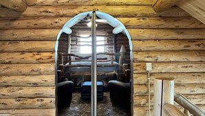 A log cabin interior with a central hallway leading to a bed area.