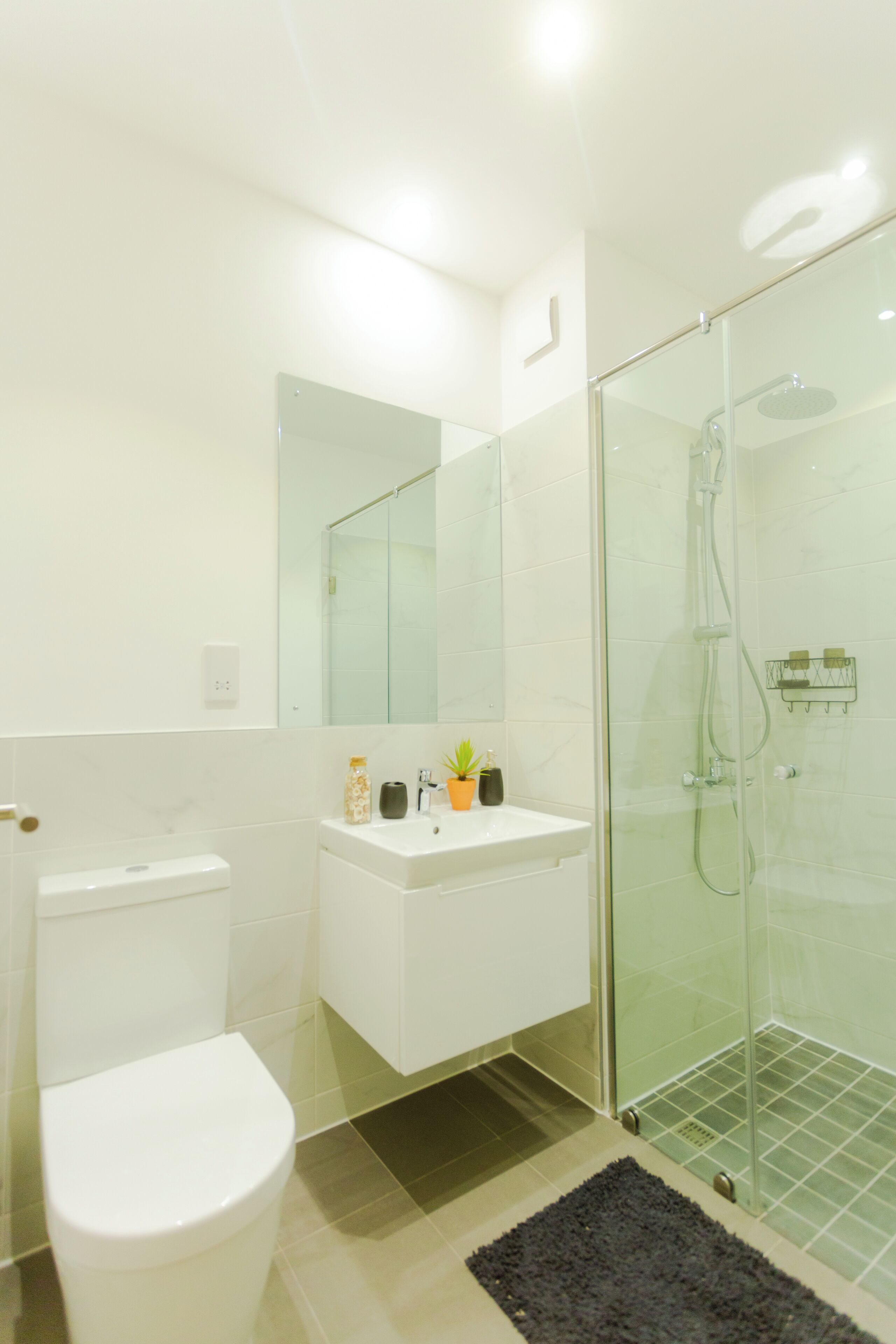 Une salle de bain moderne équipée de toilettes, d’un lavabo et d’une douche à parois de verre.