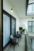 A balcony with wicker chairs, a small table, and potted plants.