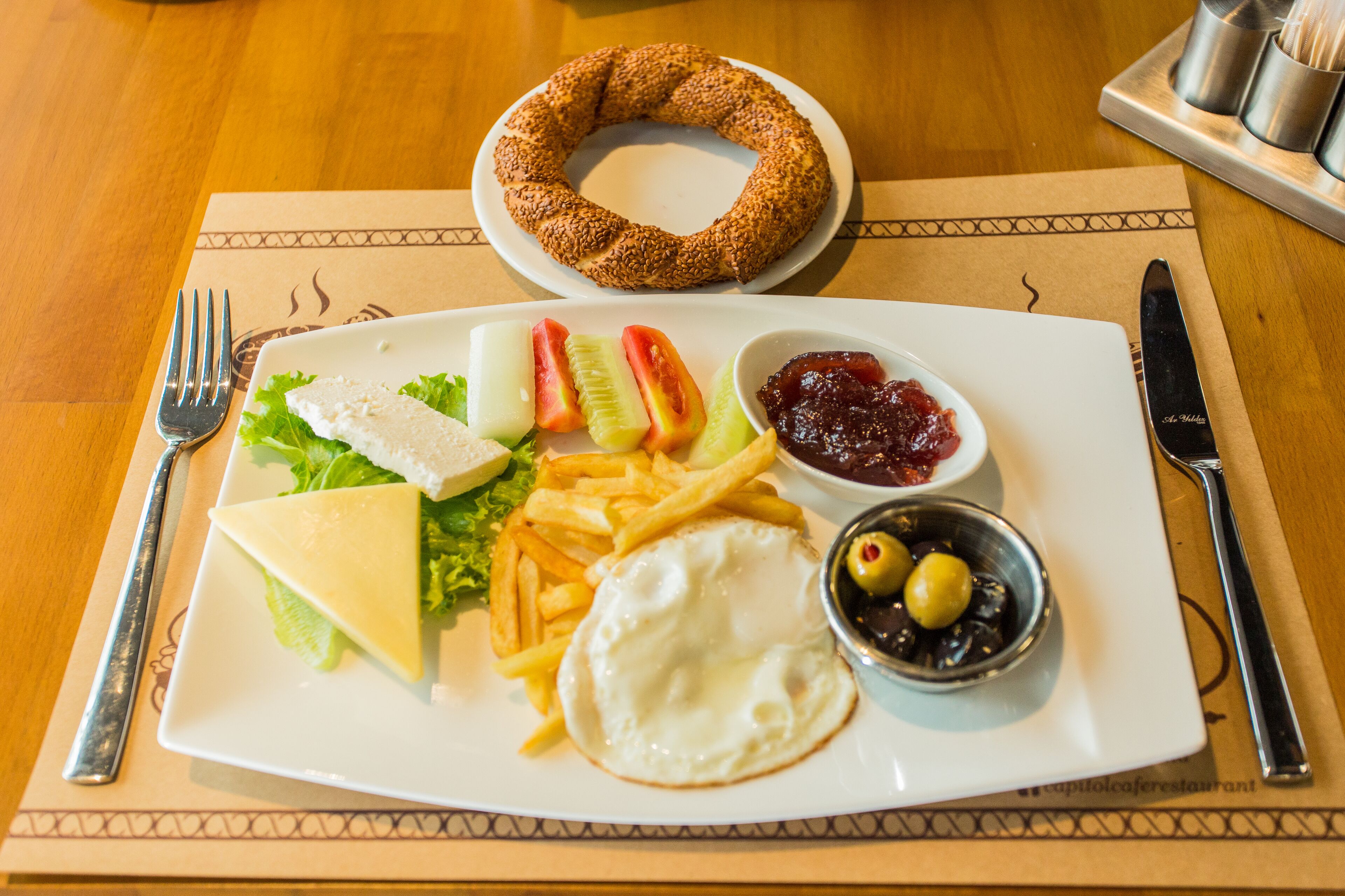 A plate of food with a sandwich, fries, a fried egg, and a side salad.