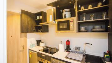 A compact kitchen with built-in appliances, wooden cabinets, and a dish drying rack.