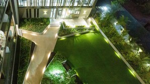 A landscaped courtyard with a green lawn, pathways, and various plants.