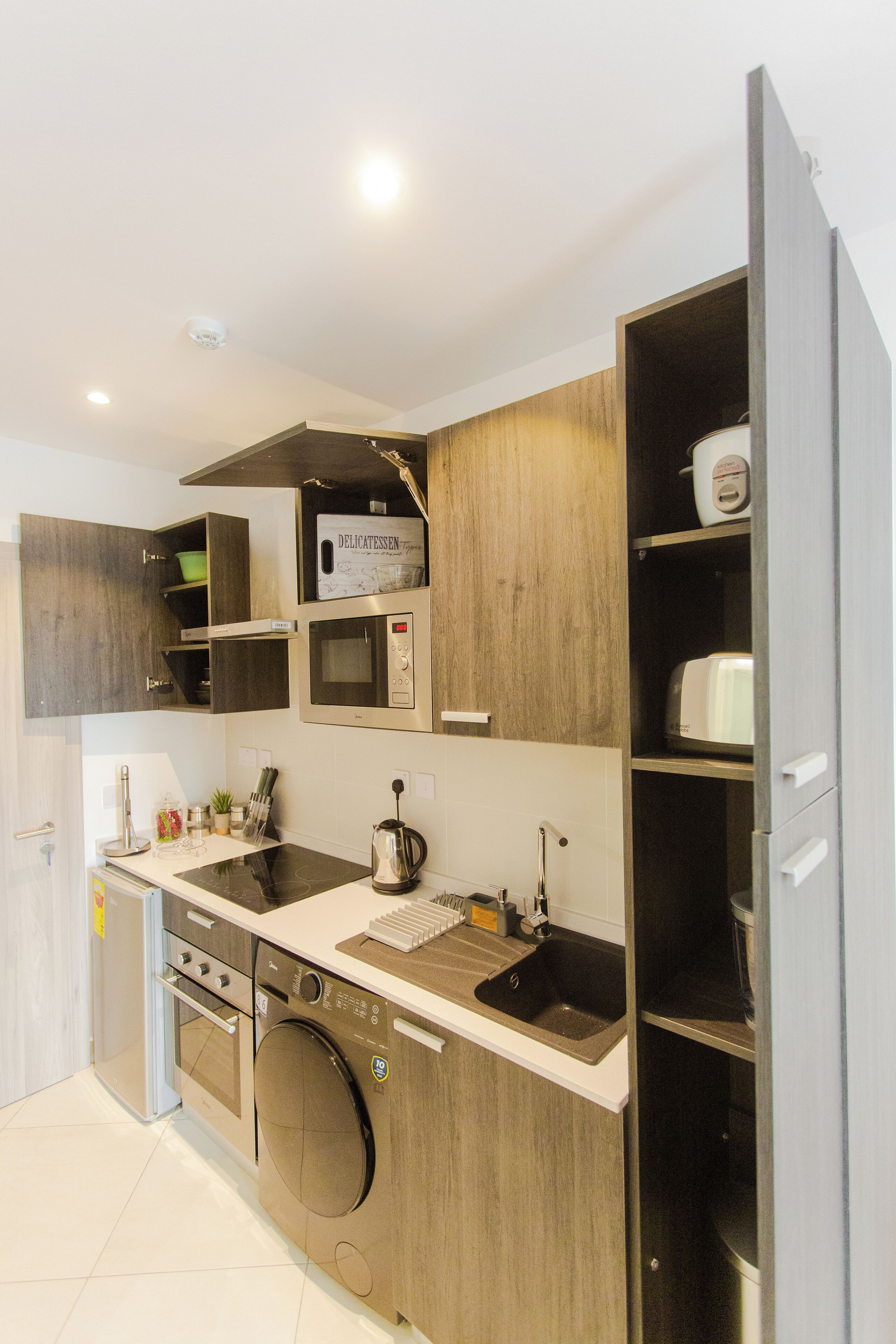 A modern kitchen with wooden cabinets, a built-in oven, a microwave, and a dishwasher.
