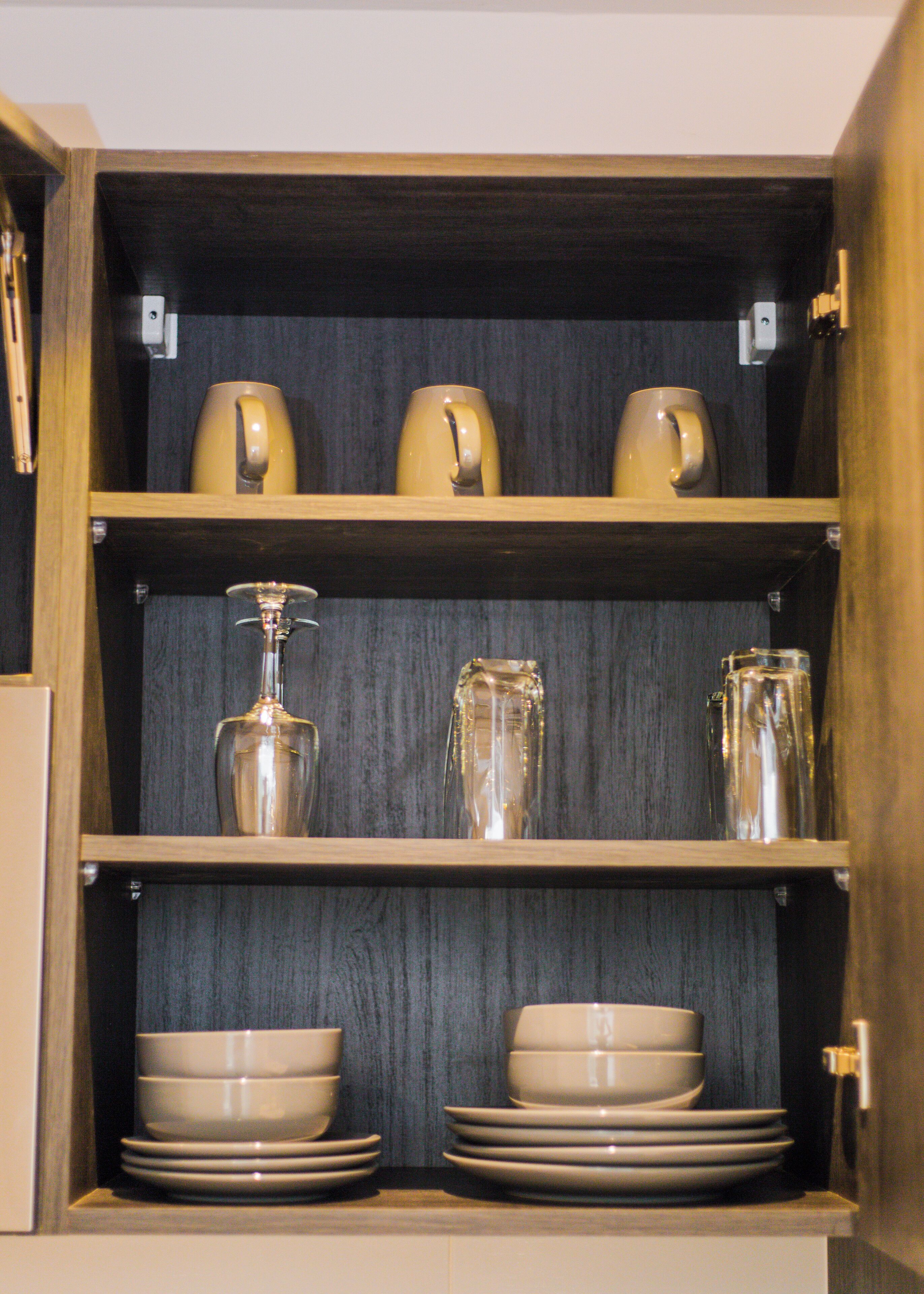 A wooden cabinet with shelves holding various glassware and bowls.