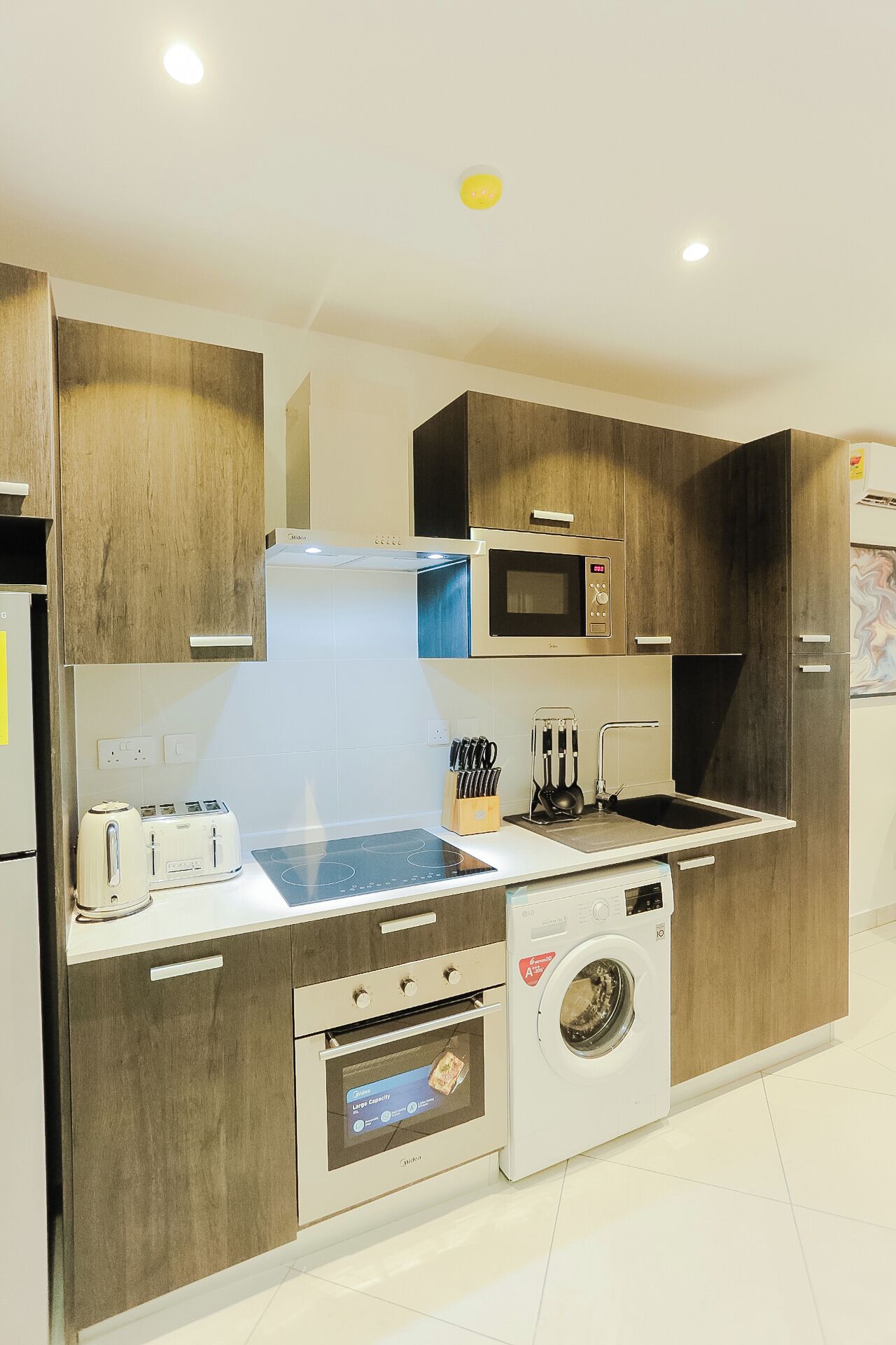 A modern kitchen with built-in appliances, a microwave, a toaster, a sink, and a washing machine.