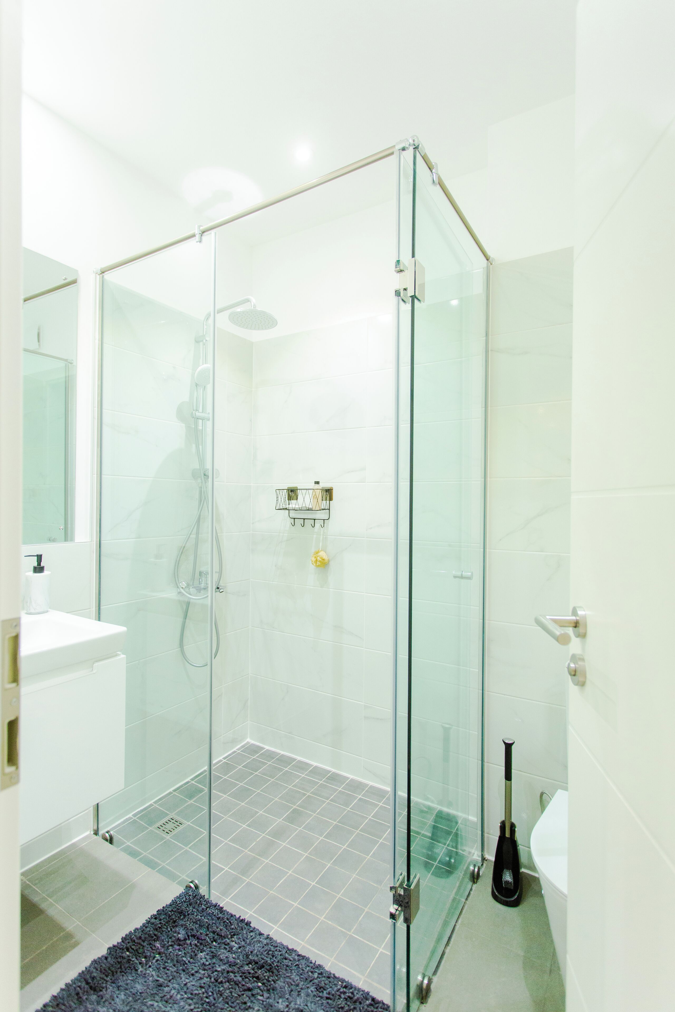 A modern bathroom with a glass-enclosed shower, a white sink, and a toilet.
