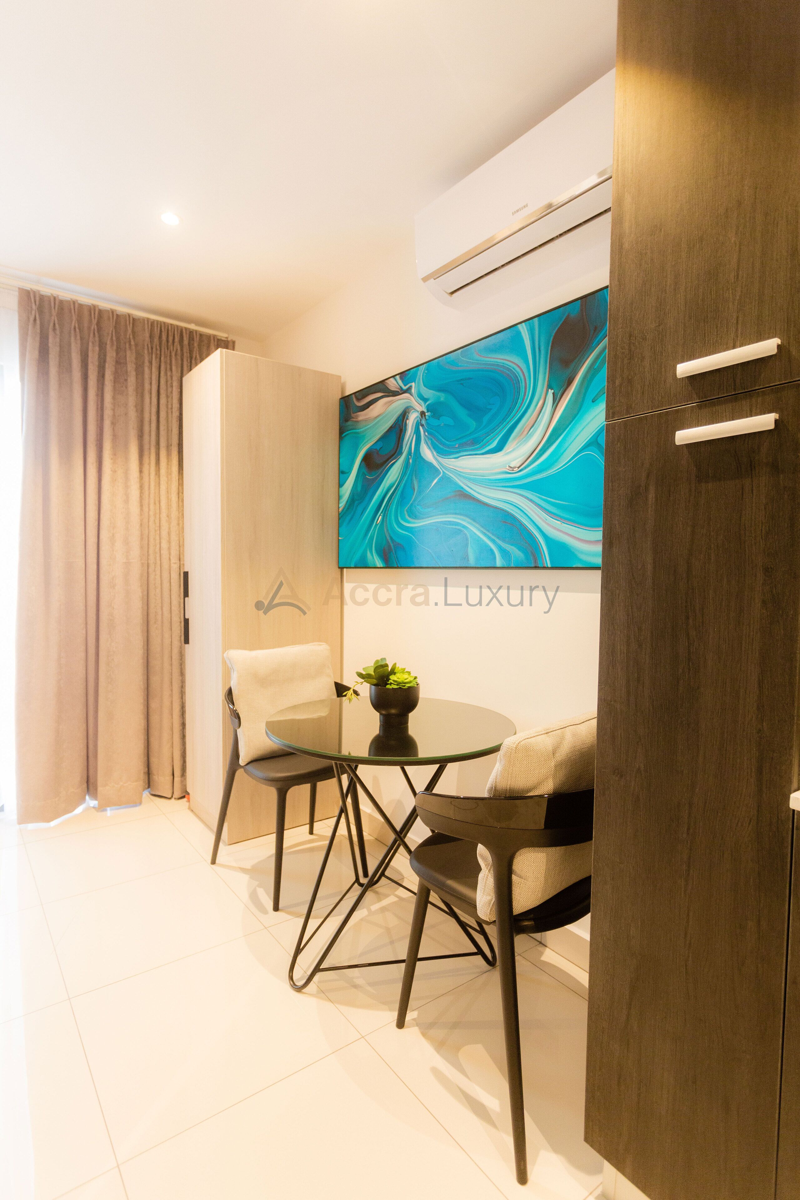 A modern room with a dining area, a large abstract painting, and a wooden wardrobe.
